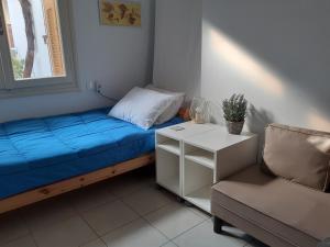 a bed with a blue blanket and a chair in a room at Kampos Rooms in Palaiochora