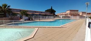 een groot zwembad met een hek eromheen bij Jardins de Neptune - villa en résidence avec piscine in Saint-Cyprien