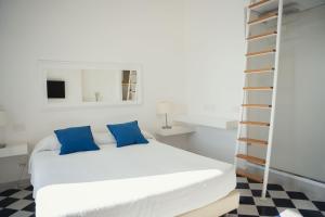 1 dormitorio con cama blanca y almohadas azules en Ganimede Centro Storico, en Sperlonga