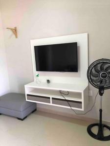 un centro de entretenimiento blanco con TV en la pared en Apartamento A em Crato-Ce próximo ao centro en Crato