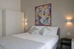 ナポリにあるF.Rooms Napoliの白いベッド1台付きのベッドルーム1室(壁に絵画付)