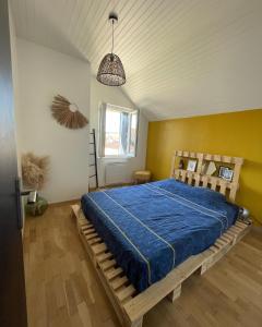 a bedroom with a bed with a blue comforter at L’ATYPIK in Chablis