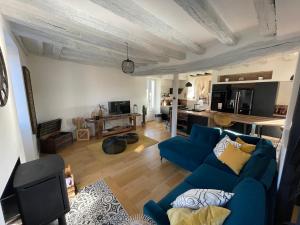 a living room with a blue couch and a kitchen at L’ATYPIK in Chablis