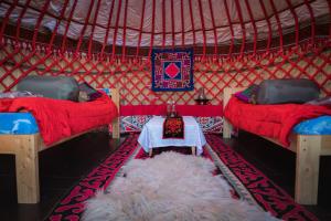 a yurt with two beds and a white rug at AK-SAI TRAVEL yurt camp at Son Kul lake in Song-Kul