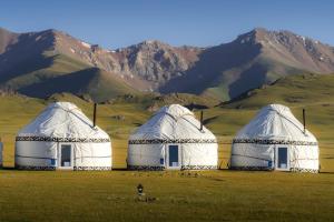 Trois dômes dans un champ avec des montagnes en arrière-plan dans l'établissement AK-SAI TRAVEL yurt camp at Son Kul lake, à Song-Kul
