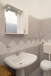 W łazience znajduje się umywalka, toaleta i lustro. w obiekcie Casa malacala w mieście Calabernardo