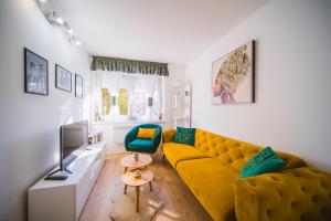 a living room with a yellow couch and a tv at Apartment Sacramento centar Varaždin in Varaždin