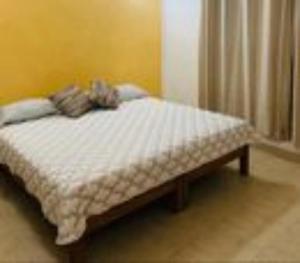 a small bed in a room with a yellow wall at Casa Jacome in Acapulco