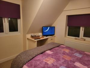 a bedroom with a bed and a computer on a desk at Tarn Cottage in Skegness