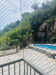 a view of a swimming pool through a fence at A casa azul em frente a praia ambiente familiar in Guarujá