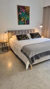 a large bed in a bedroom with a painting on the wall at Studio Sun-Beach avec parking et jardin - 500m des plages de Juan Les Pins in Antibes