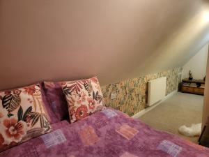 a bedroom with a bed with a purple comforter at Tarn Cottage in Skegness