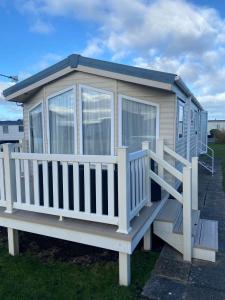 a tiny house with a porch and a deck at Orchid meadows retreat in Ashington