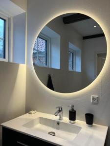 een badkamer met een wastafel en een ronde spiegel bij Dragsgaard Herregård 
