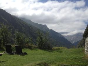 zwei Stühle auf einem Feld mit Bergen im Hintergrund in der Unterkunft Ferme de Trabés *** in Gèdre