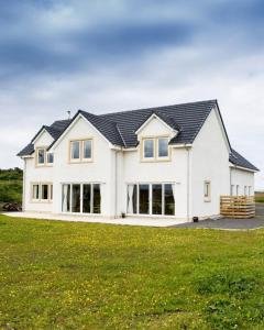 a large white house with a black roof at Stroma, Dunnet, spacious holiday house with sauna. in Brough