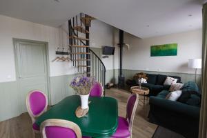 a living room with a green table and purple chairs at Le Jardin-chambres d'hôtes en Baie in Cahon