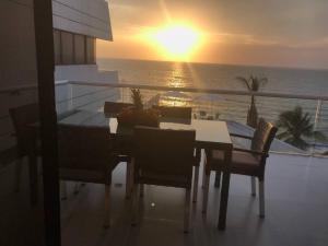 d'une table et de chaises sur un balcon avec vue sur le coucher du soleil. dans l'établissement El Encanto Beach House, à Santa Marta