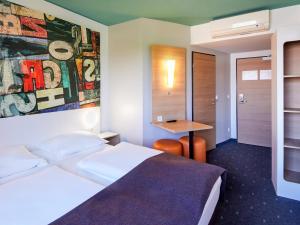a hotel room with a bed and a table at B&B Hotel Mainz-Hechtsheim in Mainz
