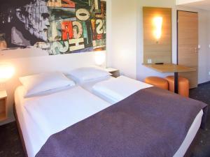 a bedroom with a white bed and a table at B&B Hotel Mainz-Hechtsheim in Mainz