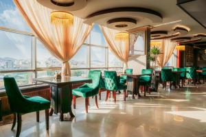 a restaurant with green chairs and tables and windows at فندق إيفا إن in Abha