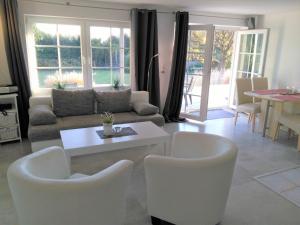 sala de estar con sillas blancas y sofá en Villa Vogelsang VO3, Schwimmbad, Sauna, en Sierksdorf