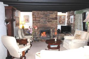 a living room with a stone fireplace and white furniture at Mellowvean in St. Agnes