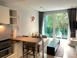 Private apartment at Emerald Terrace في شاطيء باتونغ: مطبخ وغرفة معيشة مع طاولة وأريكة