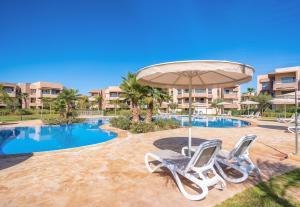 a swimming pool with two chairs and an umbrella at Apart Confort Front Pool-Garden in Marrakesh