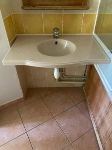 a white sink in a bathroom with a tiled floor at Studio cabine 5 personnes in Monflanquin