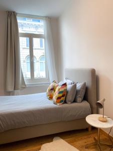1 dormitorio con cama con almohadas y ventana en New Cozy Apartments In Porte de HAL, en Bruselas