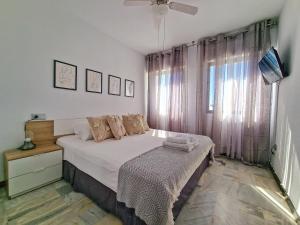 a bedroom with a bed with white sheets and a window at Hermoso Piso en La Cala de Mijas con vistas al mar in La Cala de Mijas +37 photos