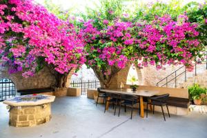 een tafel en stoelen onder een bos roze bloemen bij The Old Town House in Rhodos-stad