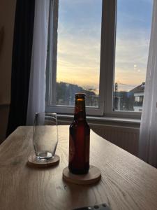 una botella de cerveza sentada en una mesa junto a un vaso en Appartement St Eloi 75m² en Saint Die