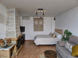 een woonkamer met een bank en een bed bij Loft Aguas de la Sierra in Benamahoma