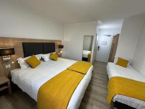 a hotel room with two beds with yellow pillows at Hôtel NOROTEL in Brumath