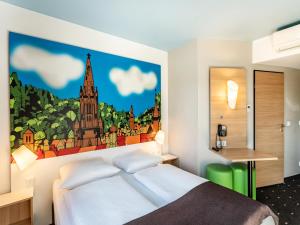 - une chambre avec un lit orné d'une peinture murale dans l'établissement B&B Hotel Freiburg-Süd, à Fribourg-en-Brisgau