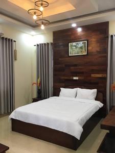 Schlafzimmer mit einem großen Bett mit einem Kopfteil aus Holz in der Unterkunft Liza Boutique in Phumĭ Ta Phŭl