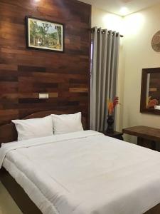 a bedroom with a white bed with a wooden wall at Liza Boutique in Phumi Ta Phul