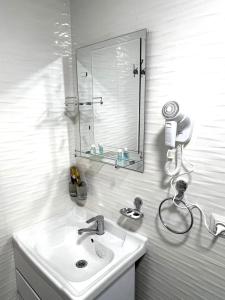 a white bathroom with a sink and a mirror at Antique Hotel Rizvan in Bukhara