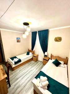 a hotel room with two beds and blue curtains at Antique Hotel Rizvan in Bukhara