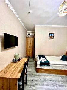 a room with a bed and a table and a tv at Hotel Rizvan Buhara in Bukhara