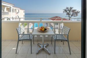 a table with chairs and a bowl of fruit on a balcony at Maria Mare Apart-hotel in Argassi