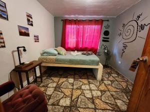 1 dormitorio con cama y ventana rosa en Boho by Arte Hostal Boquete, en Bajo Boquete