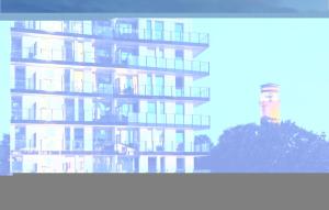 a tall apartment building with a lighthouse in the background at Highend Travemünde - Whg 215 in Travemünde