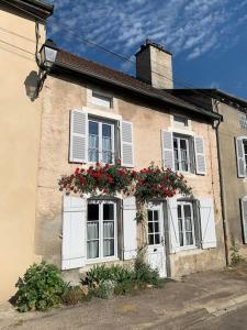 uma casa velha com janelas brancas e flores nela em Gite André De Vignory em Vignory
