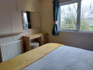 1 dormitorio con cama, espejo y ventana en Alphi 4, en Bude