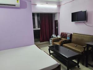 ChopanにあるHotel Sarvapriyaのベッド、ソファ、テレビが備わる客室です。