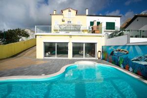 a house with a swimming pool in front of a house at Whale Song in Feteiras