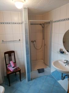 ein Badezimmer mit einer Dusche, einem Waschbecken und einem Stuhl in der Unterkunft Gästehaus Burg Molbach in Kreuzau